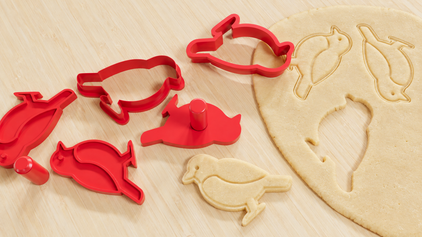 Render de cortadores y sellos rojos con forma de pájaro y mangos separados, impresiones en una lámina de masa y una pieza recortada con forma de pájaro
